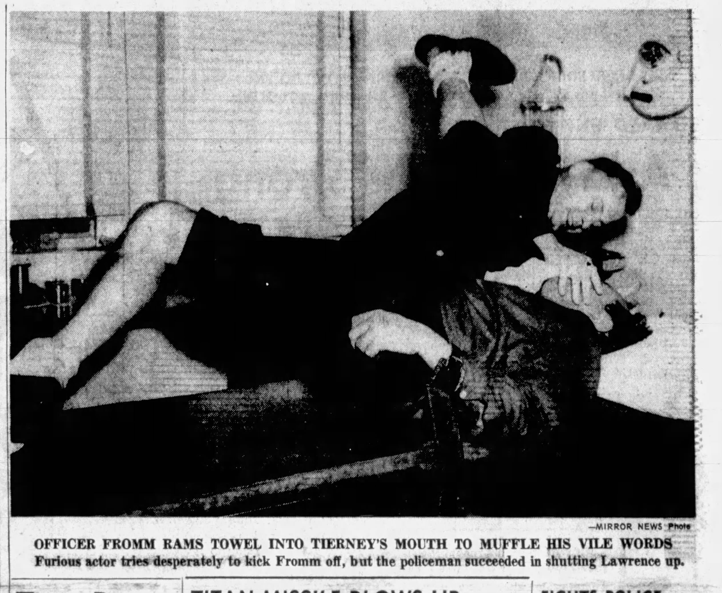 December 12, 1959: A police officer rams a towel into the mouth of actor Lawrence Tierney, lying on his back, to "muffle his vile words." 