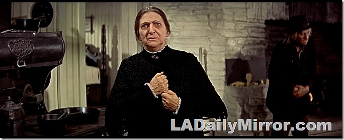 April 22, 2022, Mystery Photo. Older woman in antique kitchen. Making pained gesture