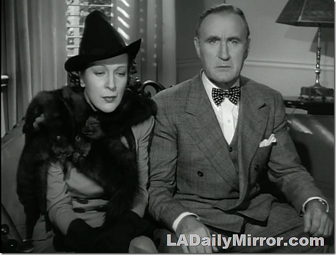 Mystery couple. The woman is wearing a fox fur and looks down. The man wears a three-piece suit and bow tie