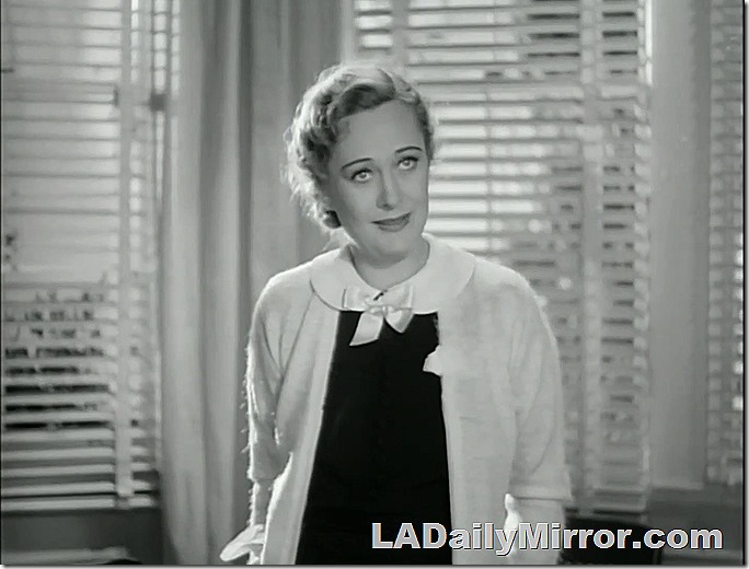 Woman backlit from windows through venetian blinds. Large collar with bow over sweater