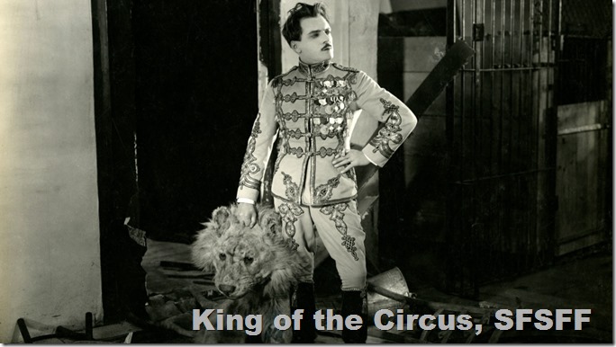 Max Linder in an elaborate lion tamer outfit holds the head of a lion costume