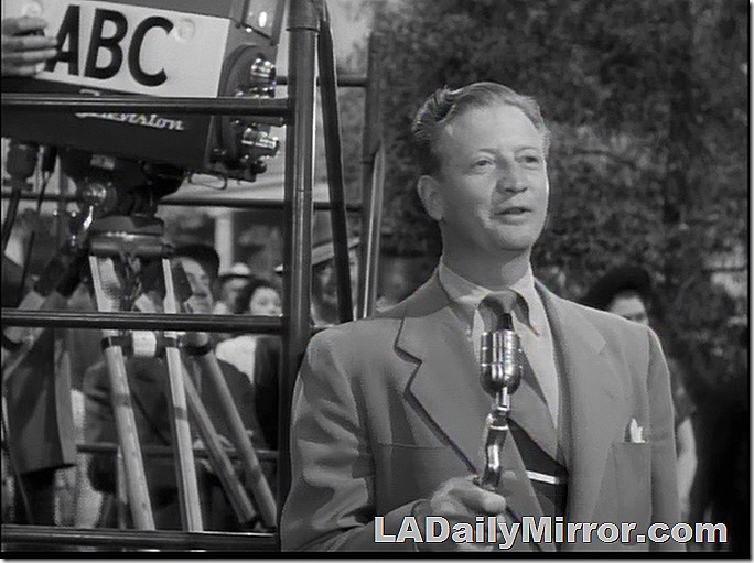 Man holding microphone next to television camera