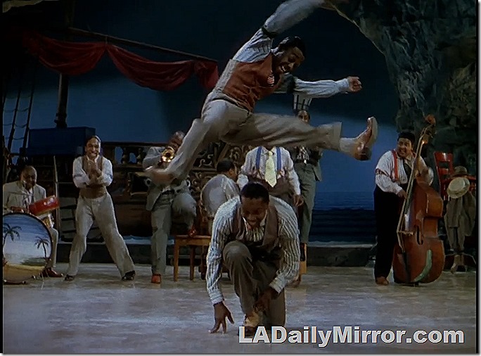 A dancer leaps over another dancer 