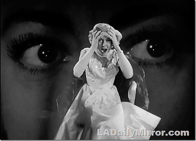 Background of someone's eyes. A woman clutches her forehead and screams. 