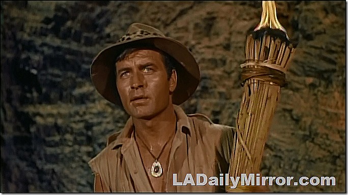 Adventurer in cave with tiki torch. His shirt is open to expose a mysterious amulet around his neck. 