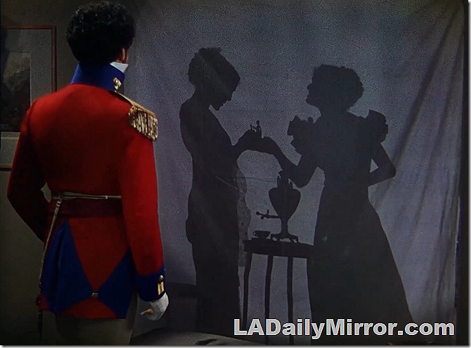 A man in uniform looks at two women in silhouette. 