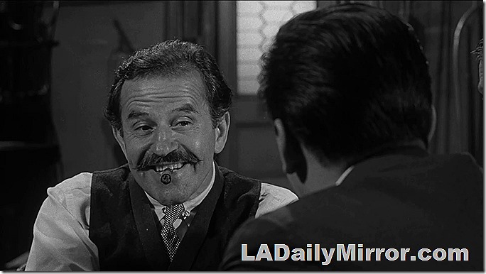 Man with mustache. Wearing vest and smoking cigar.