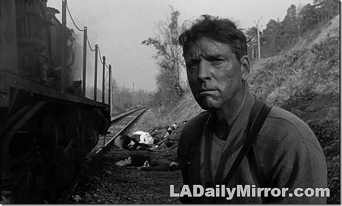 Mystery leading man alongside disabled train. Not seen: His machine gun