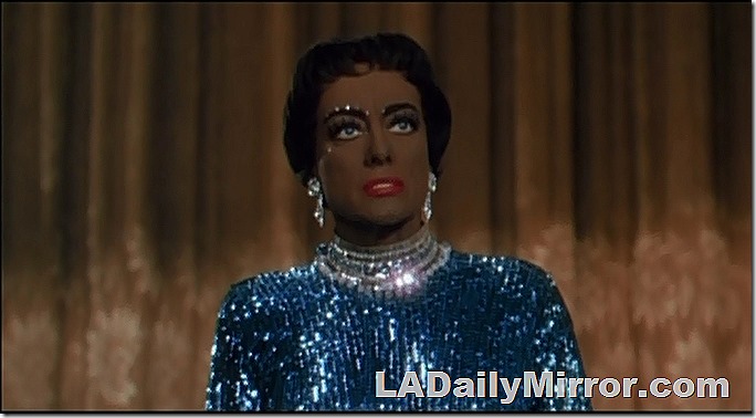 Our mysterious leading lady, in a glittery blue dress and large earrings, is in blackface. 
