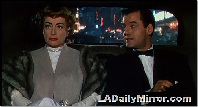 Mystery man in the back of a car. He's wearing a tux and bowtie. 