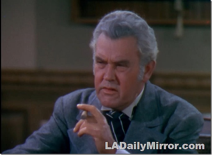 A may with gray hair. Holding a cigar. He has a studious look. 