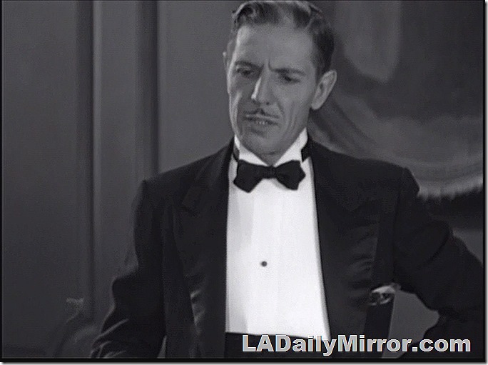 Dressy man in tuxedo. Black hair with a bit of gray and a slim mustache. 