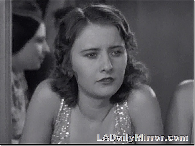 Woman in sparkly dress, lost in thought. 