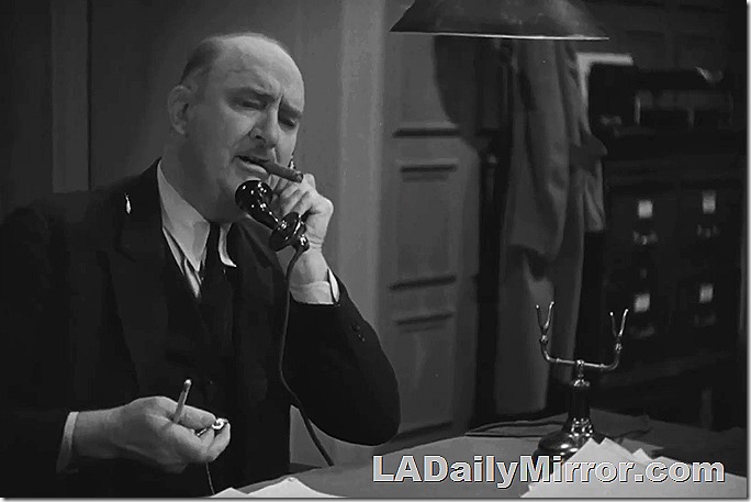Bald man smoking cigar talks on the telephone.