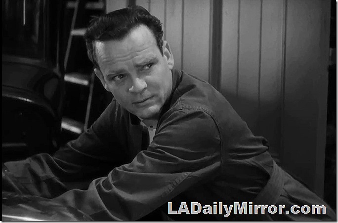 Man in coveralls, leaning over. 