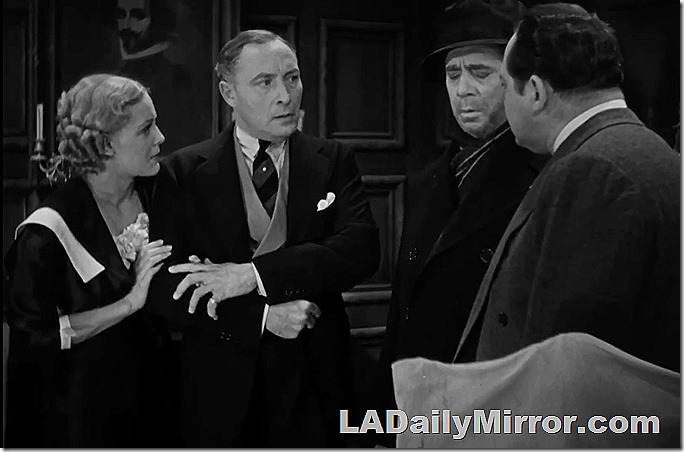 A woman clutches the arm of a mystery man. The next fellow has his eyes closed. He is wearing a coat, hat and scarf. Also Back of the Head Guy