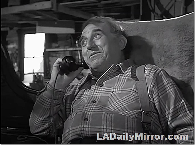 Man in plaid shirt and suspenders talking on phone