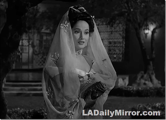 Woman with dark hair, wears dress with elaborate veil