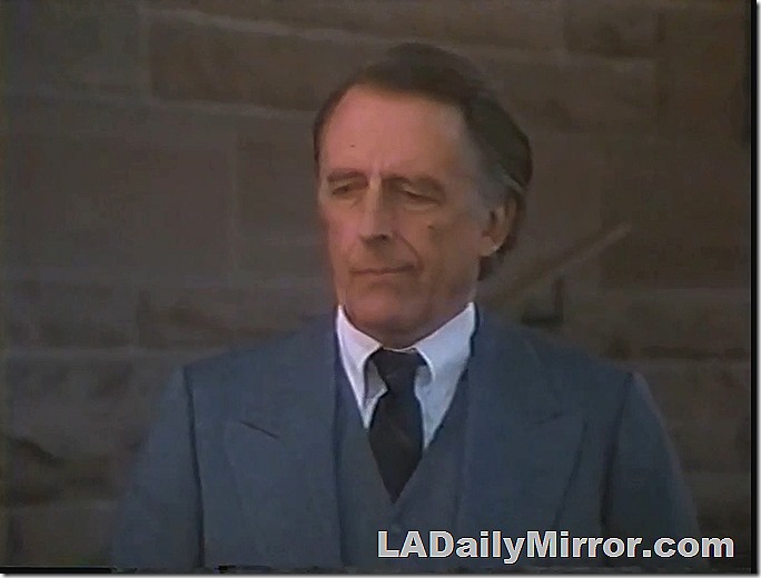 Older man in gray three-piece suit with wide lapels. 