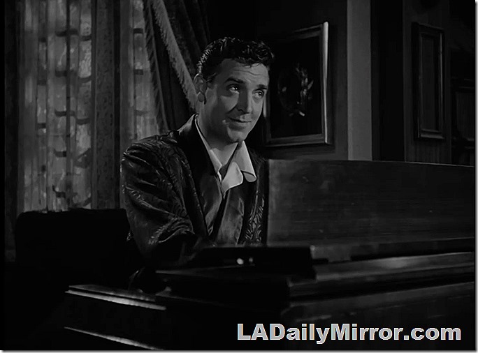 Man in dressing gown playing an electronic organ. 