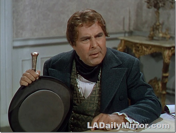 Dapper fellow with a coat and vest, hat and walking stick. 