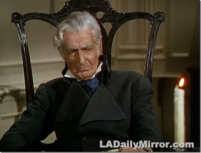 Man in high-backed chair, stiff black coat, high collar and tie