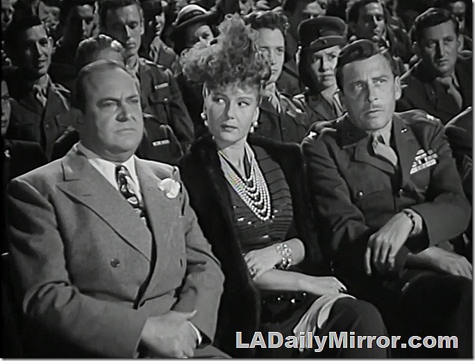 Man in civilian clothes, lady in a fancy outfit, and a military officer. 