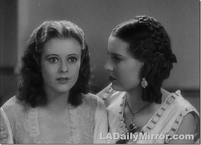 First woman is looking ahead in a somewhat started gaze. Her hair is down to her shoulders and parted in the middle. The second woman is shown on profile. She has a calm expression. 