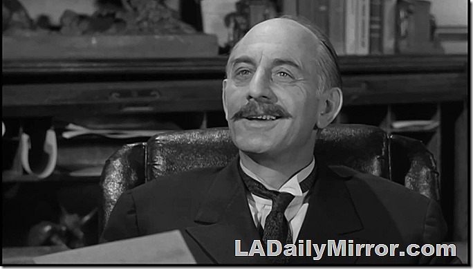 Man with a mustache, wing collar and string tie. 