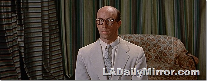 Man in white suit, tie and glasses. 