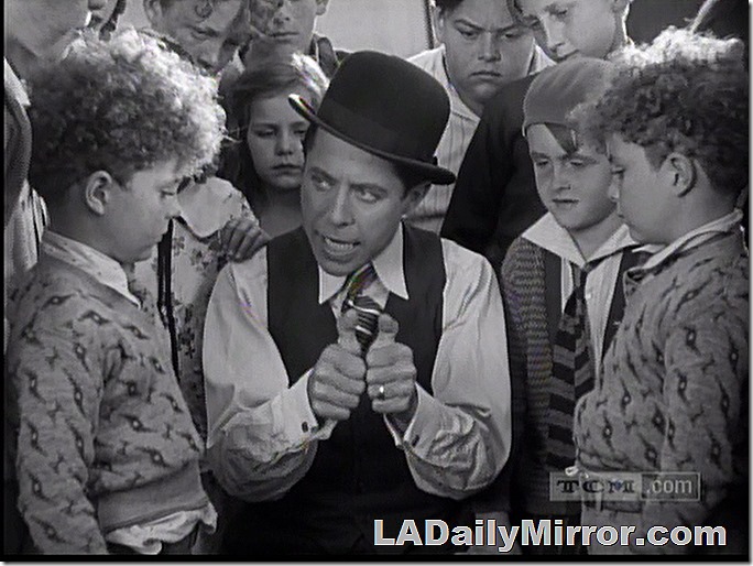 Man in derby hat demonstrates a joke for some children. 