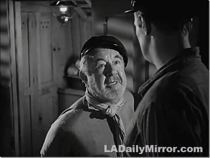 Man with beard, kerchief tied around his neck. Talking to a much taller man. 