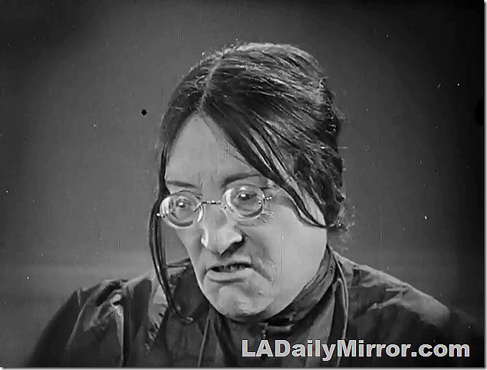 Woman with thick glasses who does not approve of such goings-on. 