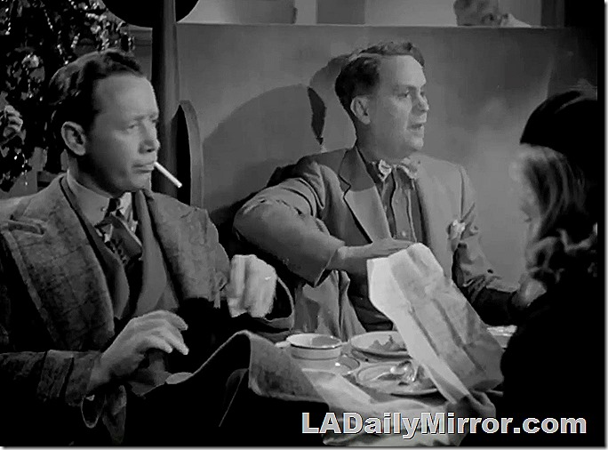 Men sitting at a restaurant booth. One is wearing a bow tie and smoking a cigarette. 
