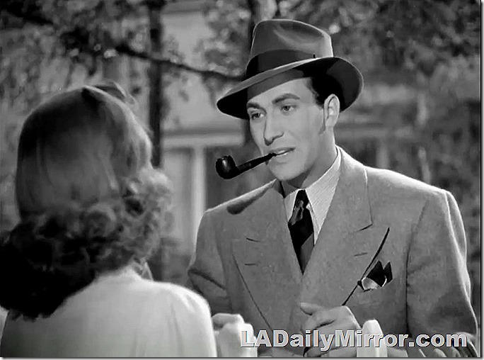 Dashing leading man in wide-lapel suit and hat smoking pipe. 