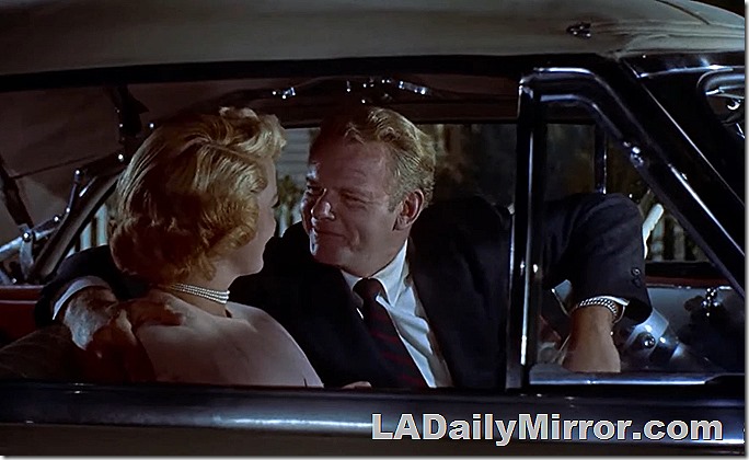 Mystery couple in covertible. The man is smiling and looking at the woman. 