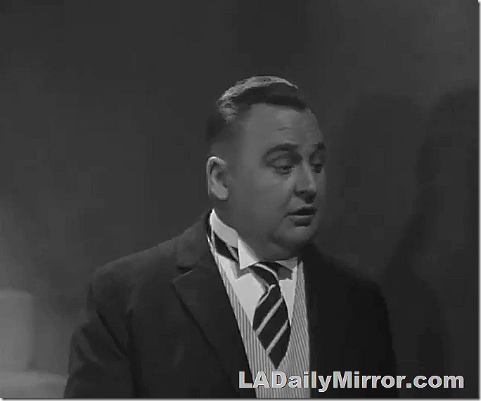 Chubby man in coat, striped vest and striped tie, with a wing collar. 