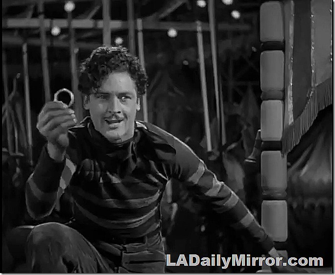 Man with mustache holding up a ring. 