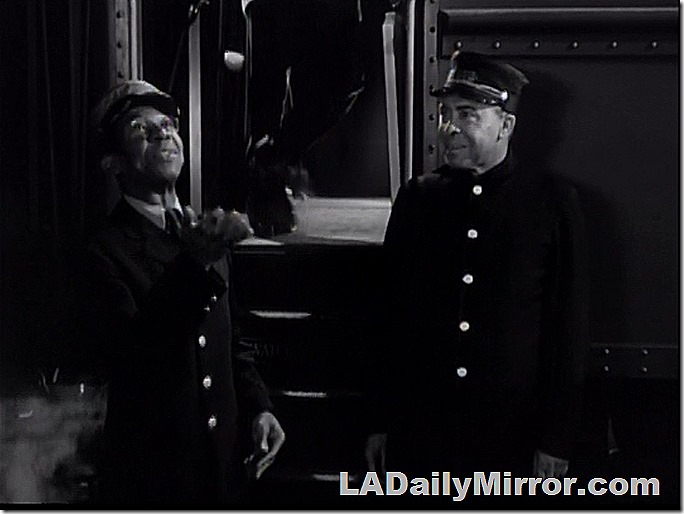 Two mysterious gentlemen next to a train.