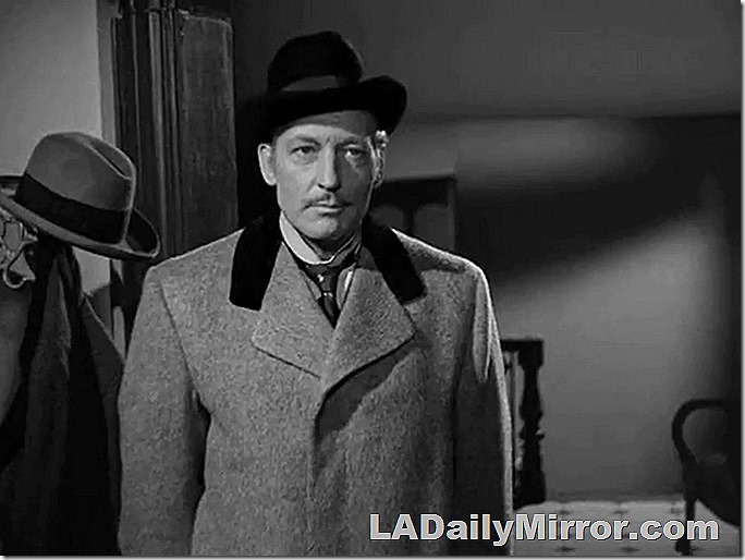 Man in hat and overcoat. Scowling. He does not approve of such goings-on. 