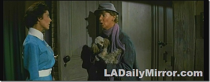 Mystery woman in blue dress with white collar and belt, mystery woman with hat and purple scarf, holding a dog. 