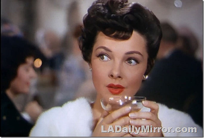 Elegant lady wearing white stole holds martini glass. 