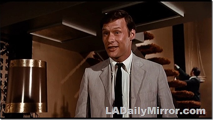 Man in light gray suit, white shirt and narrow black tie. 