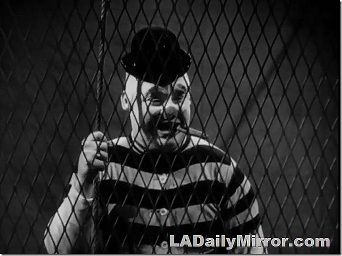 Man in clown makeup, wearing old-fashioned swimsuit, smoking a cigar and wearing a comically small hat. Man in clown makeup, wearing old-fashioned swimsuit, smoking a cigar and wearing a comically small hat.