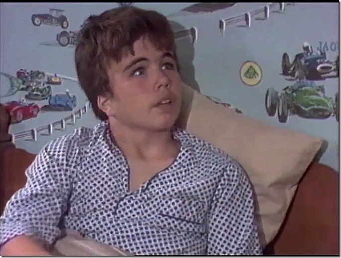 Boy with car-themed wall paper. 