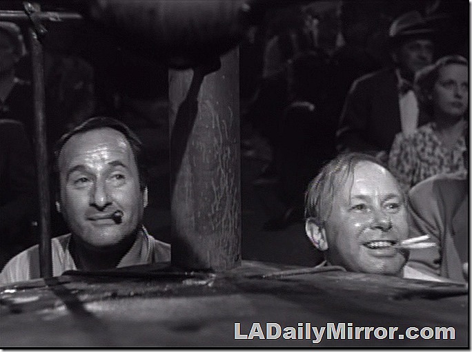 Two mysterious gents. One is smoking a cigar. The other seems to have two cigarettes going. 