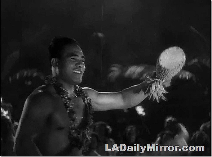 Man in native costume holds up a mysterious fruit. Or berry. Or fruit