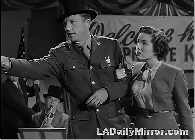 Man in uniform and top hat, with mysterious lady companion.