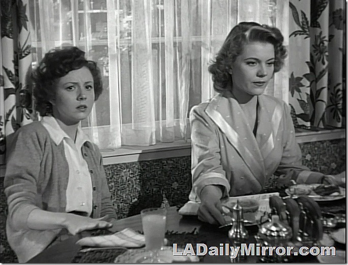 Two women at the breakfast table. They do not approve of such goings-on. One is wearing a sweater and blouse, the other is in a robe. 