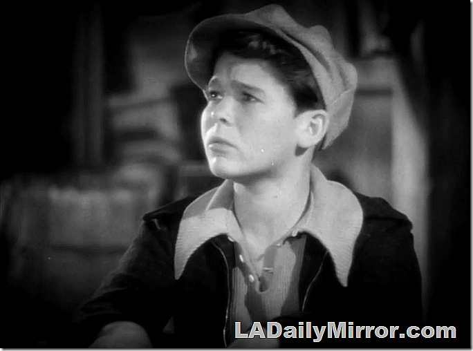 Boy in newsboy cap, shirt with open collar, and jacket. 